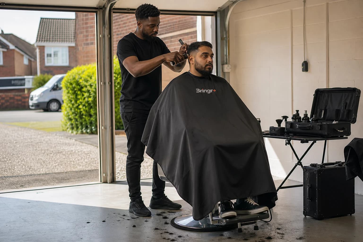 An independent mobile barber cutting a customer's hair in a clean residential garage